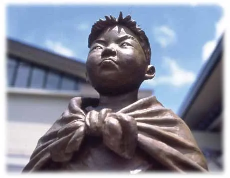 The bronze face of the boy in the cape