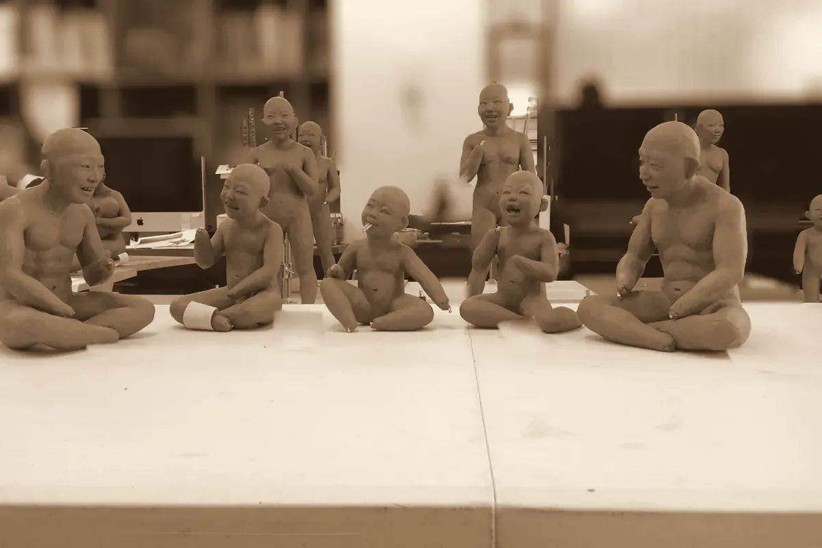 Clay doll prototypes lined up on a workbench (sepia)