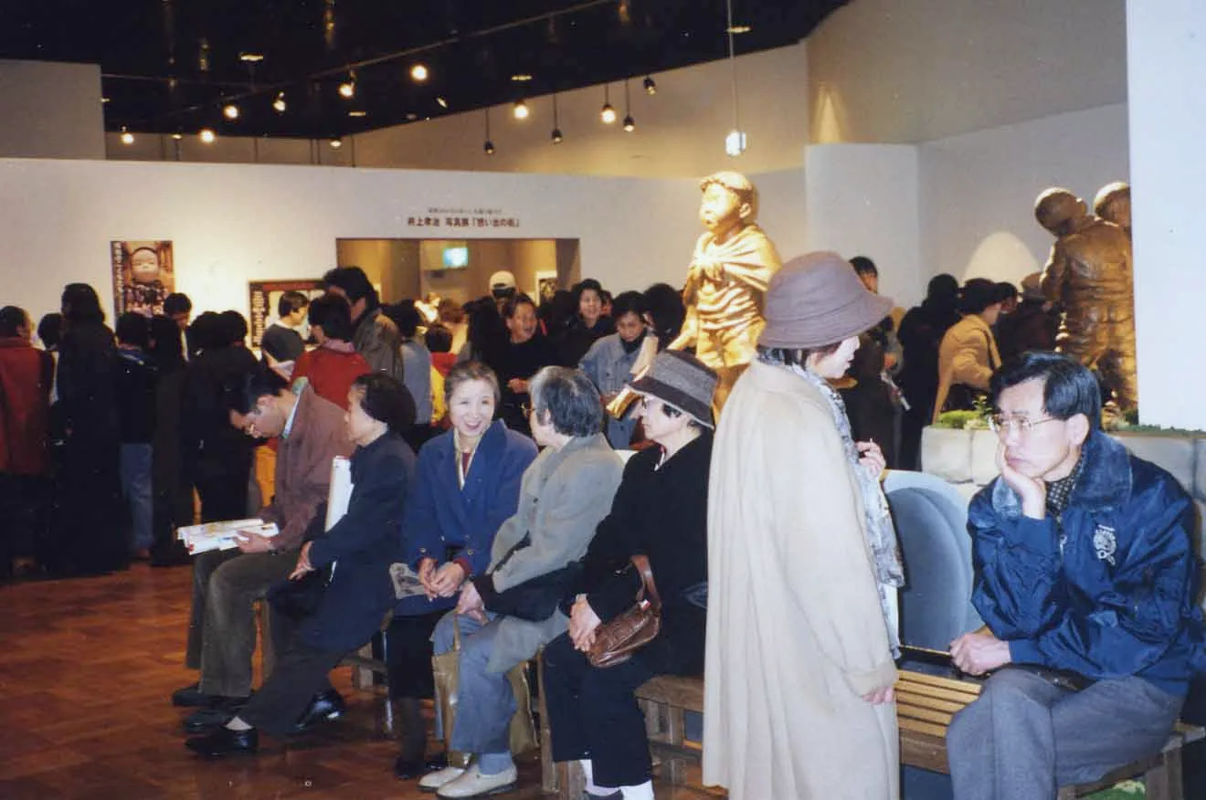 江戸東京博物館の展示会場。ベンチに座って休む来場者と、ブロンズの人形