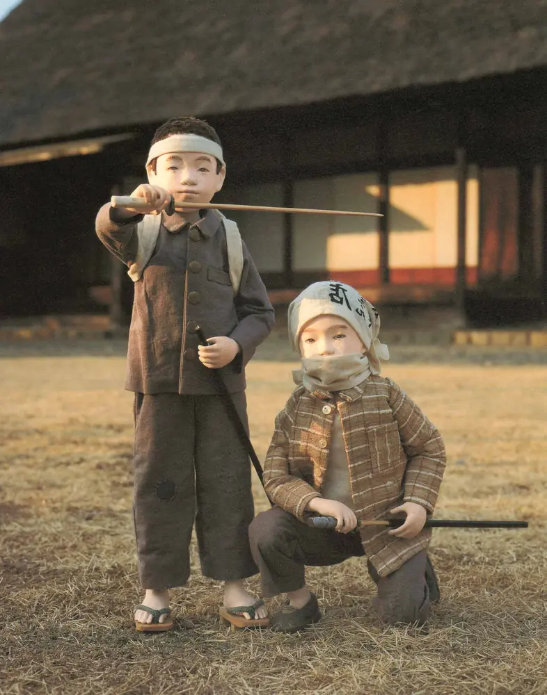 鉢巻きをして刀をかまえる男の子と、しゃがんだ男の子の人形
