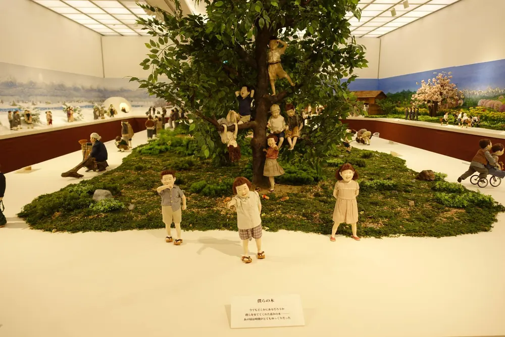 展示室の中央の大きな木と、そのまわりで遊ぶこどもたちの人形