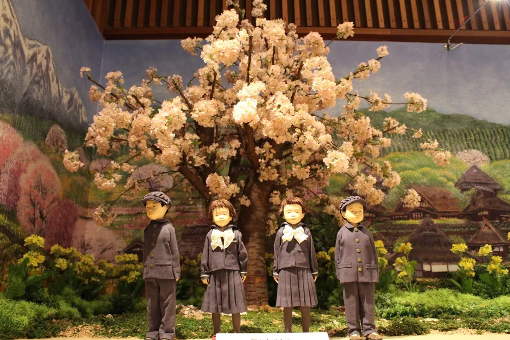 展示室のジオラマで、満開の桜の大木の下に並ぶ、制服姿のこどもたちの人形