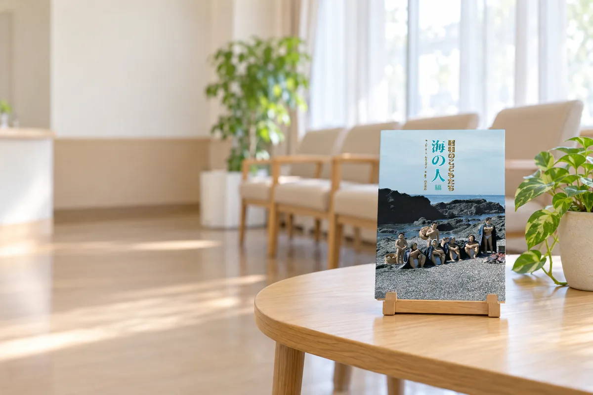 明るい待合室の低い机の上に、本立てに立てた写真集「写真物語 昭和のこどもたち 海の人編」（イメージ）