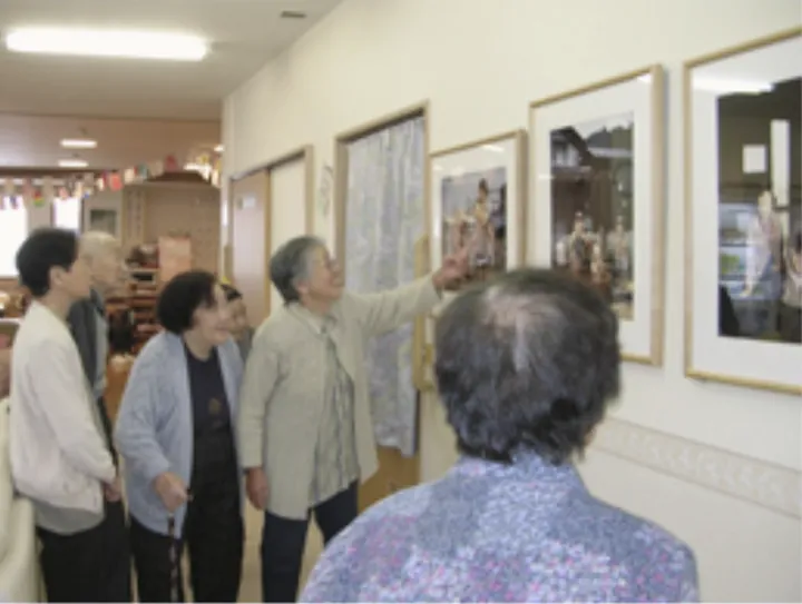廊下の壁に並べて掛けた写真パネルを、指さしながら見る人たち