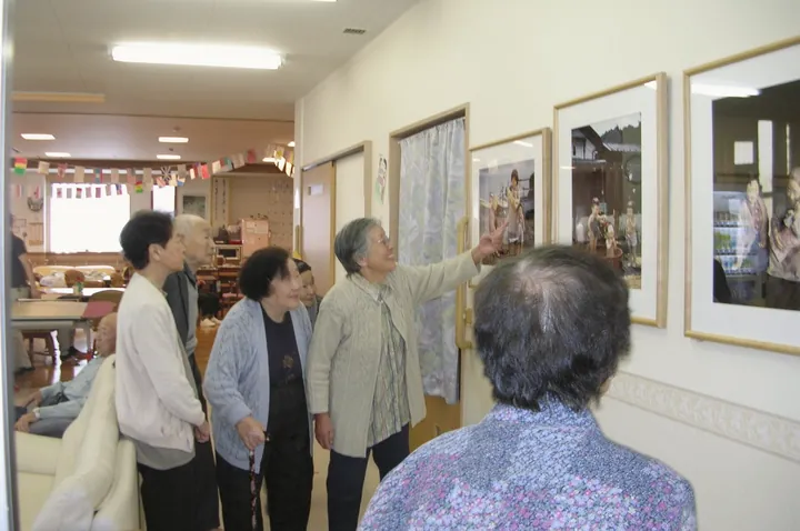 廊下の壁に並べて掛けた写真パネルを見る人たち