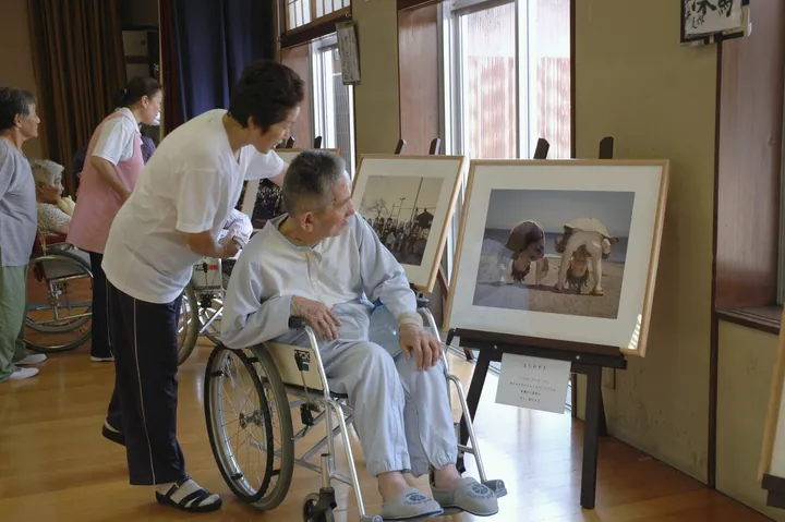 三脚に立てた写真パネルと、車いすの方に声をかける人