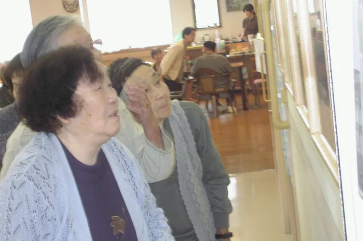 窓ぎわに掛けた写真パネルを見上げる人たち