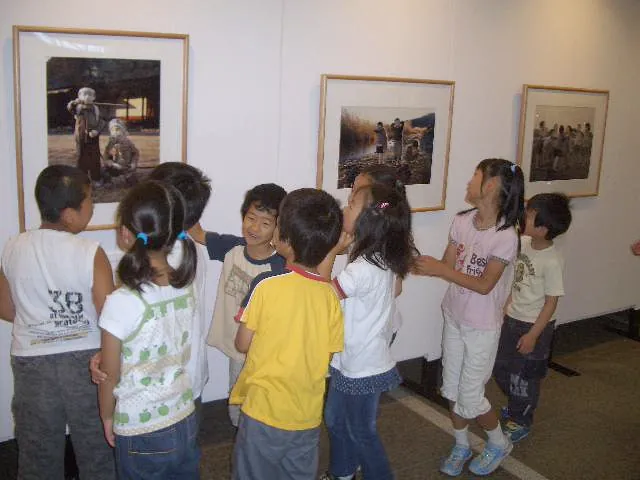 壁に掛けた写真パネルの前に集まる、こどもたち