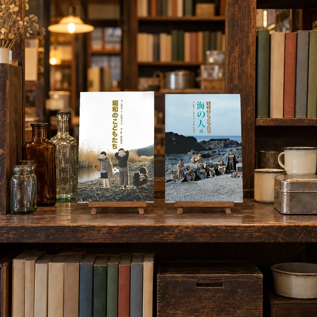 古い木の棚に、古い瓶や本と並べて、本立てに立てた写真集2冊(イメージ)